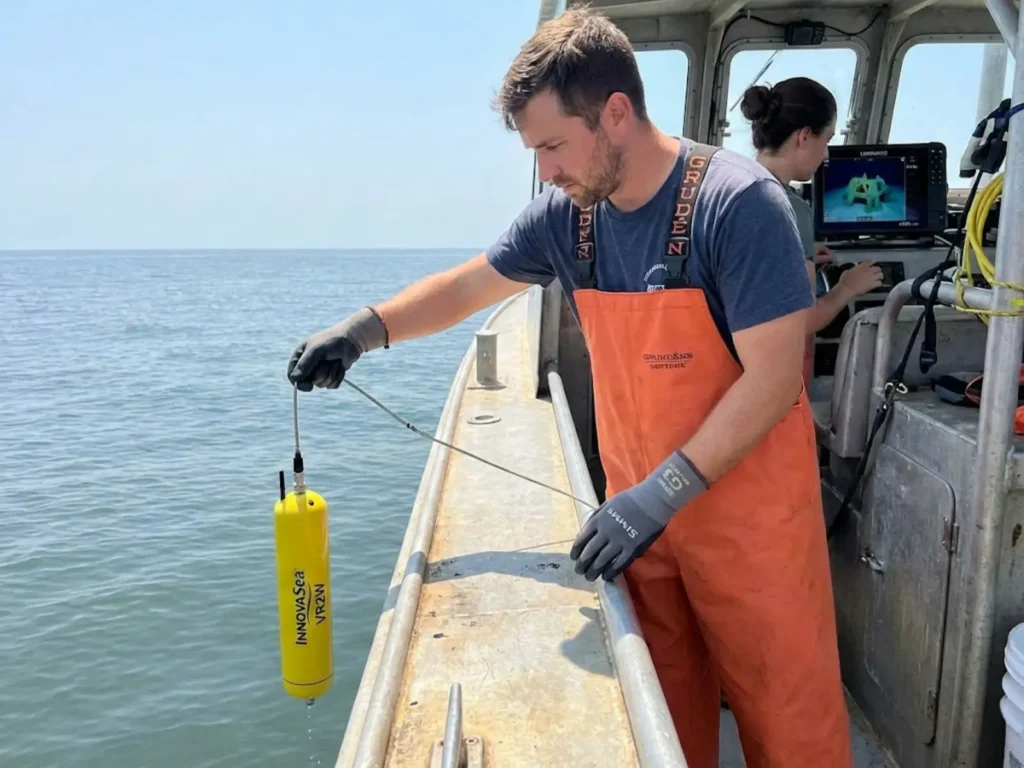 Research technician deploying acoustic receiver to track cobia migration patterns on artificial reef