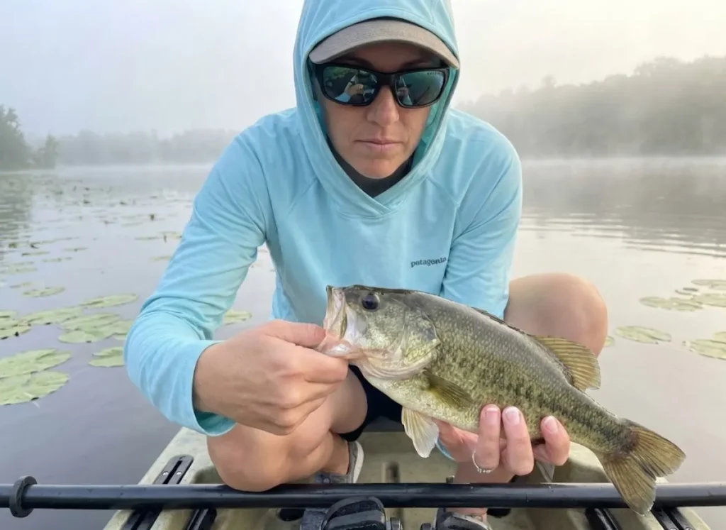 Female angler checking bass tongue for tooth patch to distinguish Spotted Bass from Largemouth