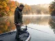Fall Bass Transition Confused You? Here’s the Depth Playbook Angler studying fish finder during fall bass transition on misty reservoir