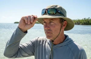 Fishing Hat Sun Protection Features: What the Tag Won’t Tell You Angler adjusting Shelta fishing hat brim while sight fishing on bright Florida flats