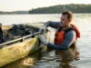 Flipped Your Fishing Kayak? Here’s How to Get Back In Angler in PFD gripping capsized Hobie fishing kayak preparing deep water reentry
