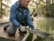 Hooked an Alligator Gar? Here’s How to Handle It Safely Angler safely handling alligator gar snout with protective gloves on Texas bayou boat