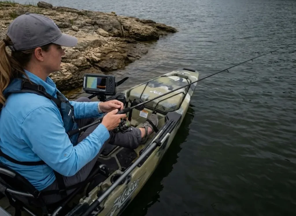 Kayak angler working drop shot rig over main lake point structure on overcast day