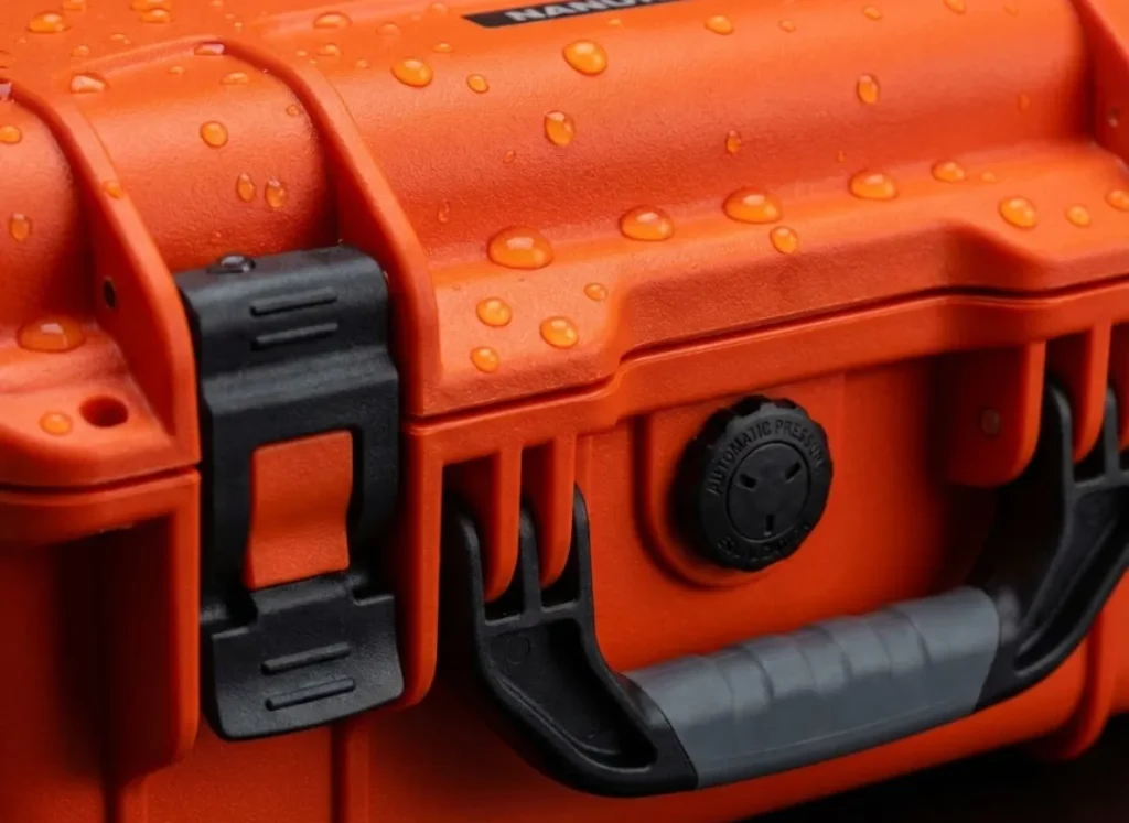 Macro detail shot of a wet orange Nanuk hard case showing the texture of the resin and the latch mechanism.