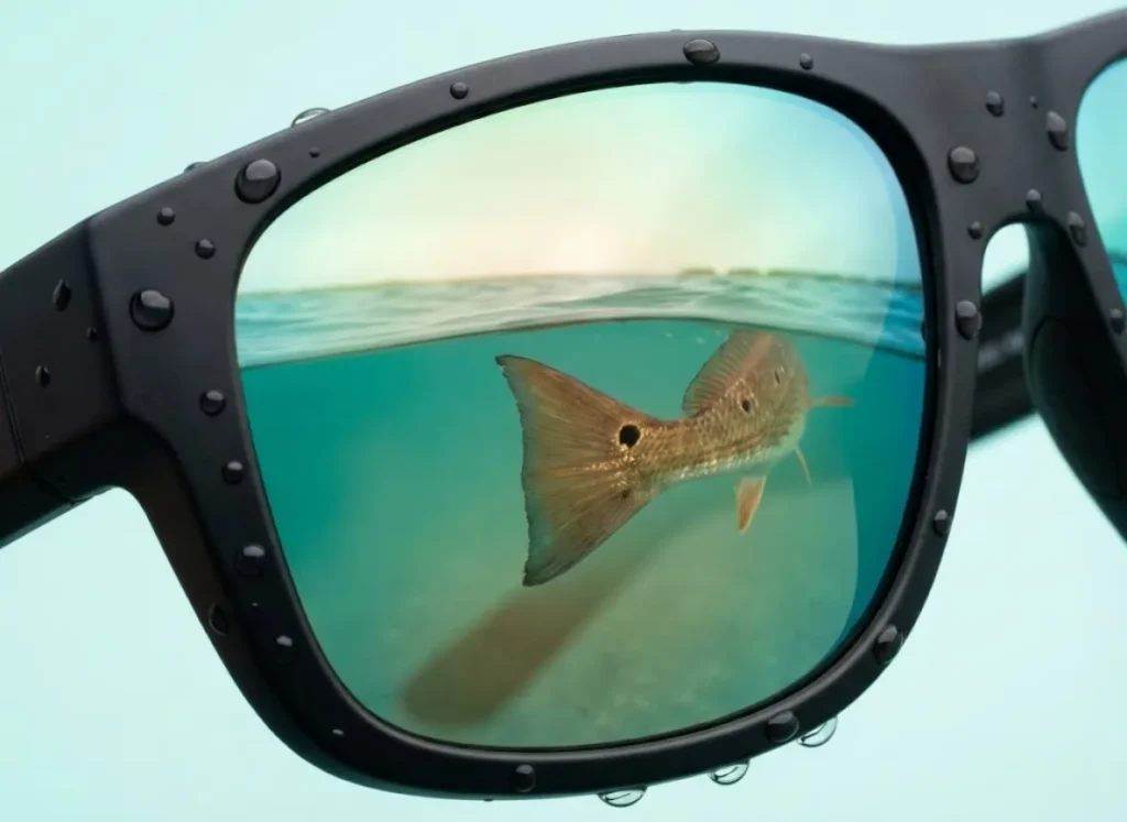 Extreme close-up of Costa polarized sunglasses with copper lenses reflecting a flats fishing scene, highlighting lens technology and clarity.