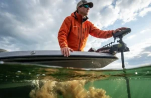 Predict Fish Movements During Rapid Water Level Changes Split-level photography of a pro angler on a bass boat above turbulent mixing water currents, wearing a Simms rain jacket, dramatic storm lighting.
