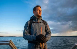 Read Cloud Formations to Predict Storms Professional angler in Simms gear standing on a boat bow, scanning a dramatic sky where cirrus clouds transition into storm clouds, symbolizing weather prediction.