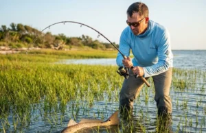 The Only Way I Can Catch Redfish in Thick Turtle Grass Angler fighting redfish in thick turtle grass flat during golden hour with bent rod