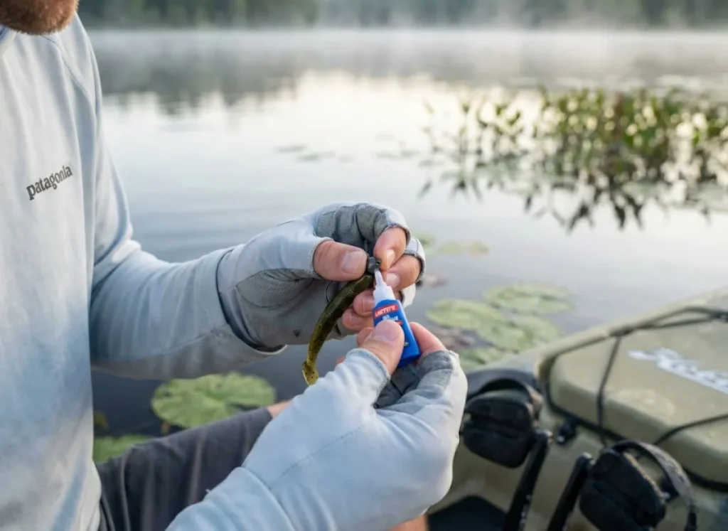 Angler applying superglue to hook when rigging ZMan ElaZtech soft plastic for weedless presentation