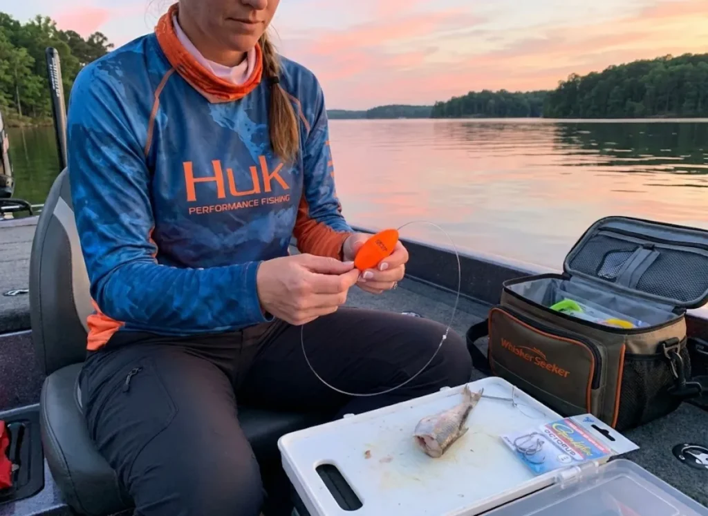 Angler rigging Santee Cooper catfish rig with peg float on Lake Gaston reservoir at dusk