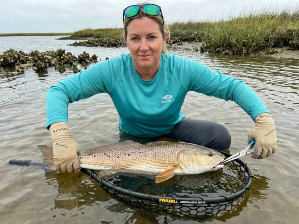 Fishing guide performing safe in-water release of redfish with single inline hook using conservation techniques
