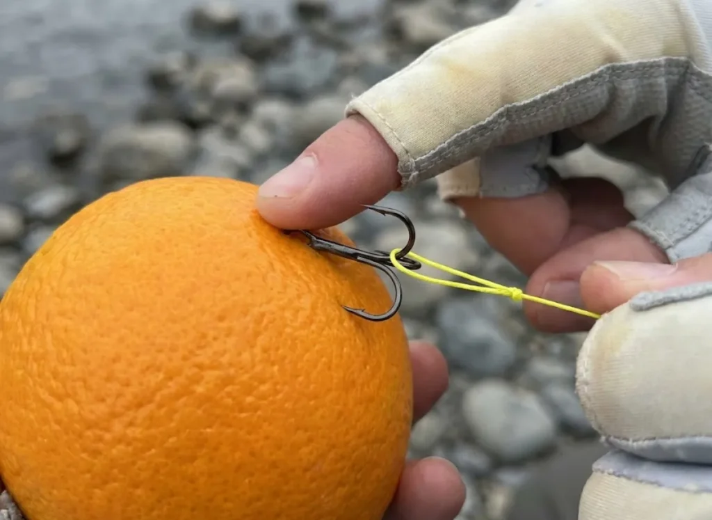 Demonstration of the string-yank method showing finger pressure on the hook eye and a yellow braid loop