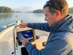 Why Striped Bass Move the Way They Do (And How to Find Them) Angler reading fish finder for striped bass at thermocline depth in Chesapeake Bay