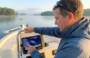 Why Striped Bass Move the Way They Do (And How to Find Them) Angler reading fish finder for striped bass at thermocline depth in Chesapeake Bay