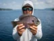 Target Big Bluegill in Deep Water A professional angler in Simms gear holding a trophy bluegill over deep open water, captured in high-resolution detail.
