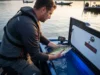 Tournament Fish Care Mistakes That Cost You Thousands Tournament angler carefully placing largemouth bass into aerated livewell while checking water temperature