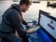 Tournament Fish Care Mistakes That Cost You Thousands Tournament angler carefully placing largemouth bass into aerated livewell while checking water temperature
