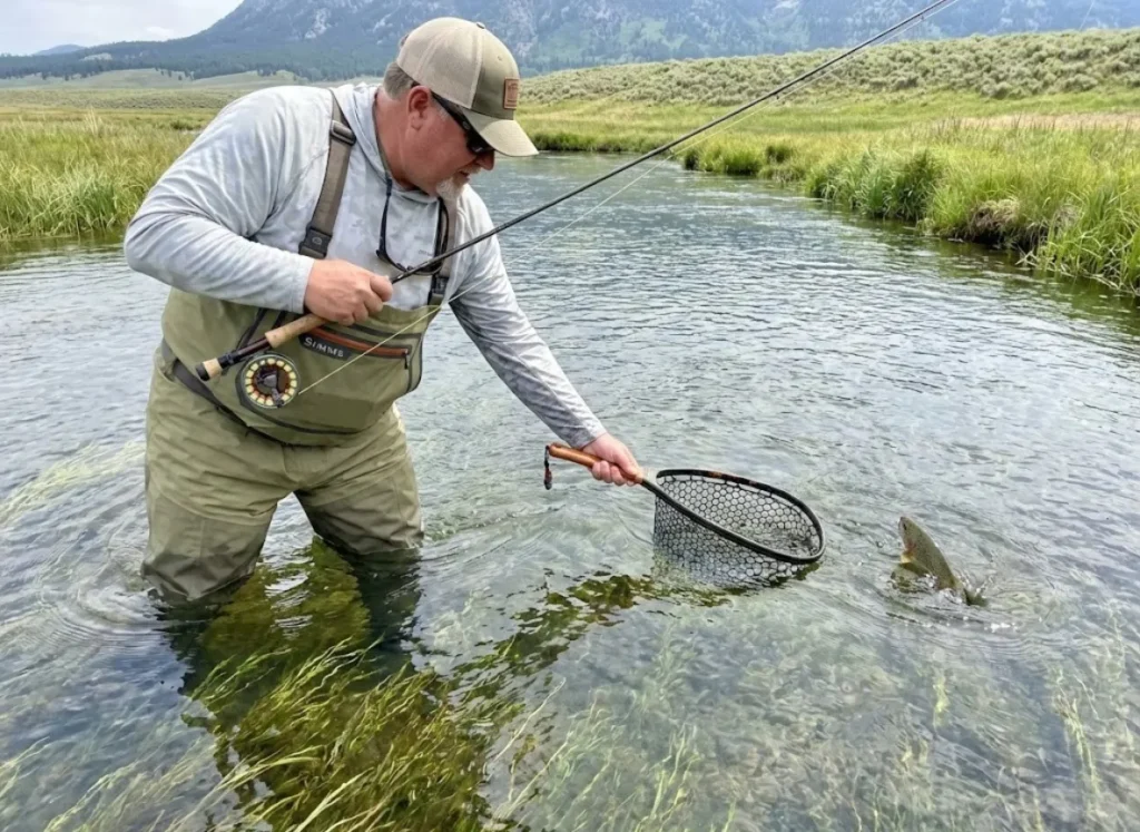 Plus-size angler in Simms King waders netting trout in spring creek with full range of motion