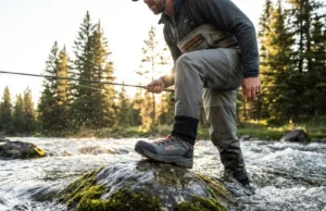 Rock or Mud? Here’s the Boot Sole That Grips Best Angler wading safely in fast current wearing Simms G3 boots on slippery rocks during golden hour