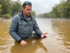 Water Turbidity Lure Visibility Explained: From Physics to Practice Angler selecting lures while wading in turbid stained water considering color visibility options