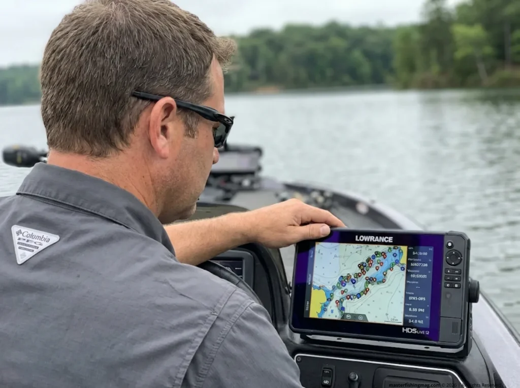 Angler studying a Lowrance HDS Live fish finder screen covered in GPS waypoints on a calm lake