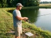 How Much Fishing Gear Do Beginners Need? 7, Not 70 Beginner angler casting a spinning combo at a pond, the small kit of fishing gear a beginner needs
