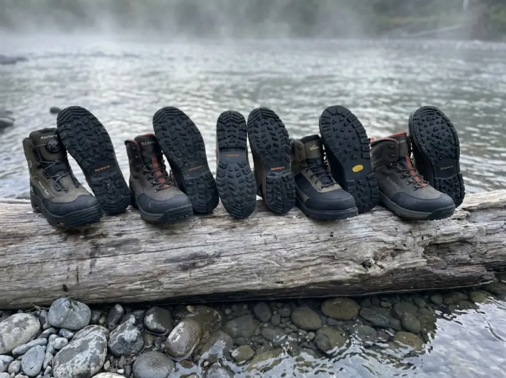 Five lug sole wading boots lineup showing tread patterns on driftwood log by river