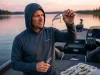 Your Crankbait Hooks Are Too Small and It Shows Angler inspecting crankbait treble hooks on bass boat at dawn with split-ring pliers