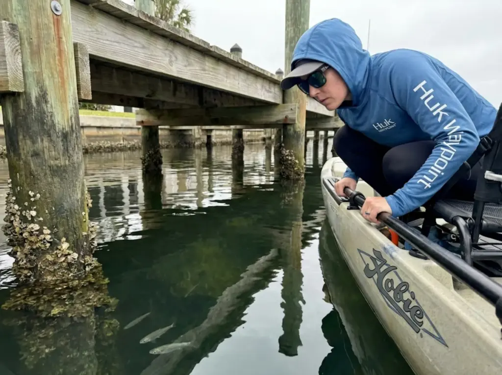 Kayak angler studying fish holding structure beneath a residential dock
