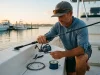 How Often to Change Your Fishing Line by Type Angler spooling fresh fishing line onto a spinning reel at a dawn boat ramp
