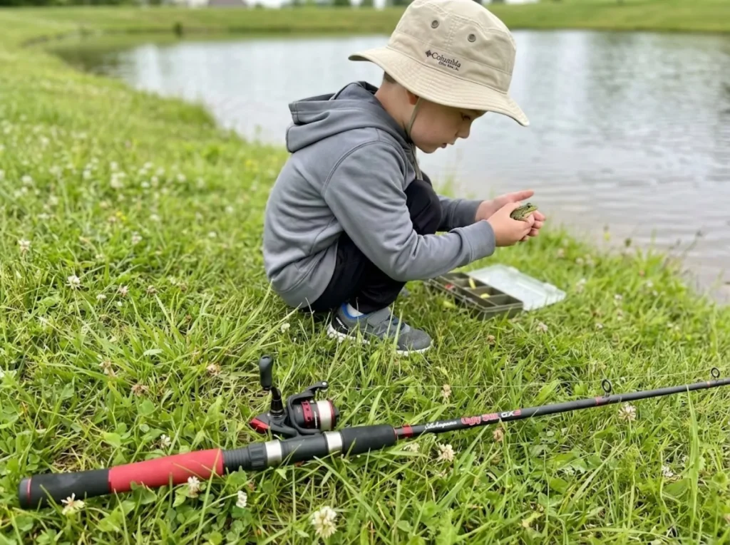 Young boy distracted from fishing by a frog showing typical child attention span at a pond