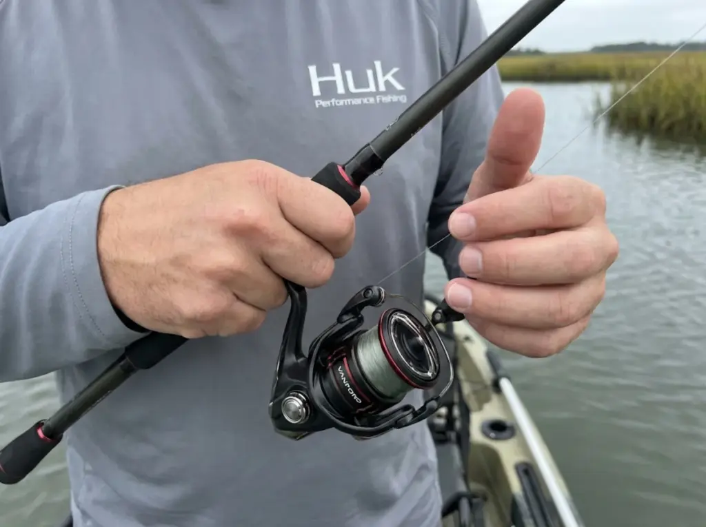 Angler manually closing spinning reel bail and pulling line taut