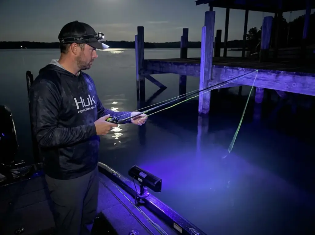 Night bass fishing under dock with blacklight and fluorescent line glowing