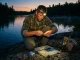 Night Fishing Headlamps That Won’t Spook the Bite Angler in a headlamp rigging tackle at dusk on a rocky bank before night fishing