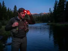 Best Headlamps for Night Fishing (Tested 6+ Months) Angler adjusting red light headlamp at dusk before night fishing on mountain river