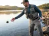 Best Portable Fish Finders for Bank Fishing (2026 Tested) Bank angler casting portable fish finder from rocky shoreline at dawn