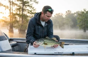 Slot Limit vs Bag Limit Explained (With Real Examples) Angler measuring largemouth bass on bump board to check slot limit compliance