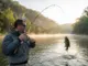 Tennessee’s Hidden Smallmouth Rivers Most Anglers Miss Angler fighting jumping smallmouth bass on a misty Tennessee river at dawn