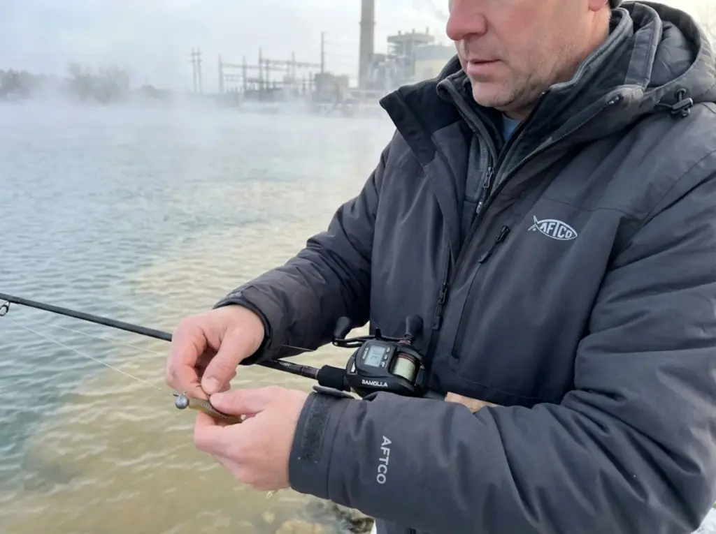 Angler using slow deadstick presentation near thermal discharge seam in winter with electronic reel