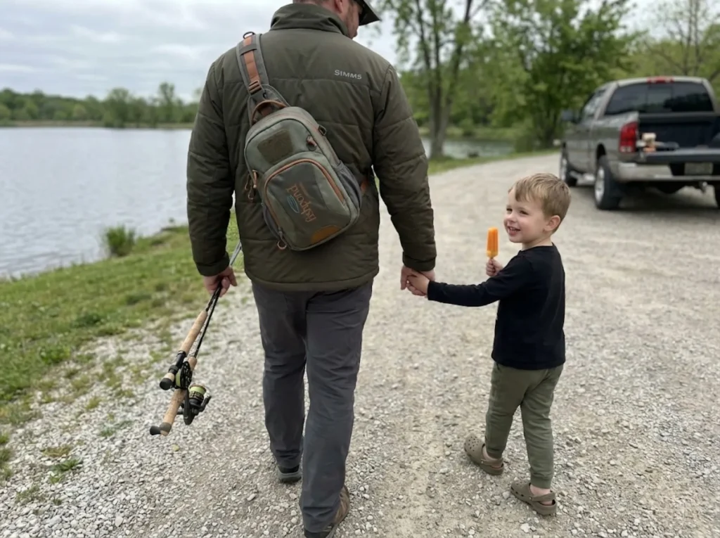 Father and child walking away from lake after ending fishing trip early on a positive note  