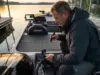 Fish Finder Won’t Show Bottom? Here’s the Real Fix Angler troubleshooting fish finder transducer at boat transom during dawn inspection