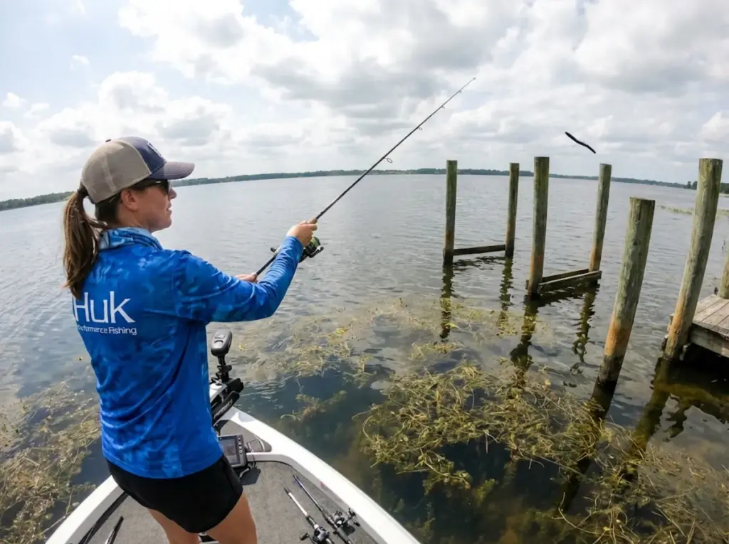 Angler casting wacky rig toward dock pilings during post-spawn bass fishing season
