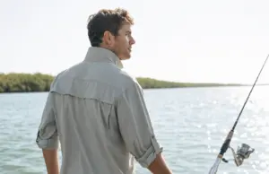 Best UPF Fishing Shirts That Survive the Wash Angler in a vented long-sleeve UPF fishing shirt on a skiff deck under high sun