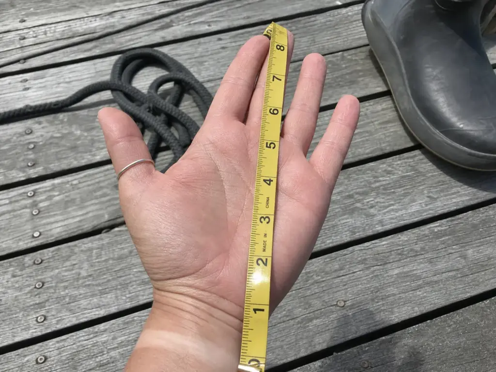 Close-up of a soft tape measuring hand length from wrist crease to middle fingertip