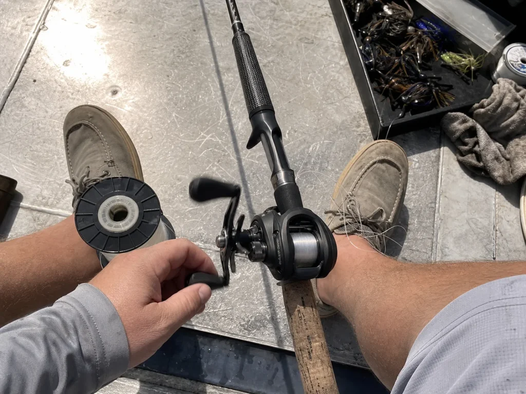 Baitcasting reel mounted on a jig rod being spooled with fluorocarbon line on a boat deck