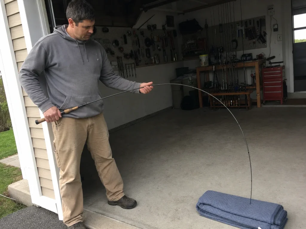 Angler slowly bending a fishing rod into an arc to reveal a flat spot or hinge in the blank