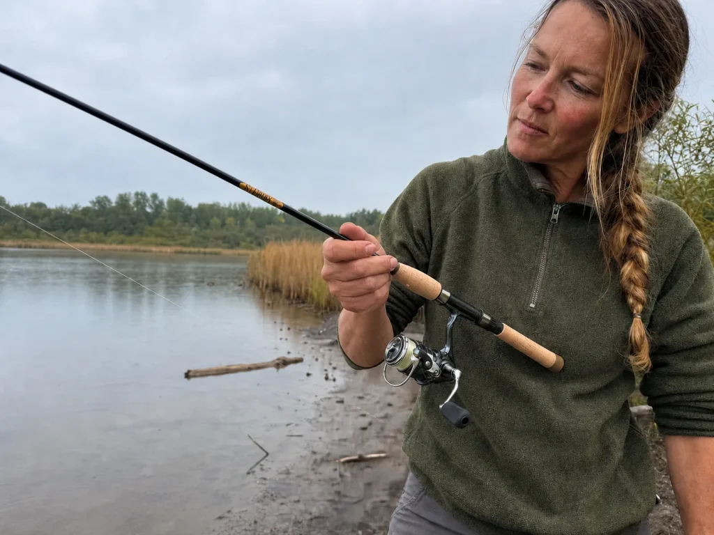 Angler feeling a light-line bite through a St. Croix Triumph spinning rod on a quiet lake bank