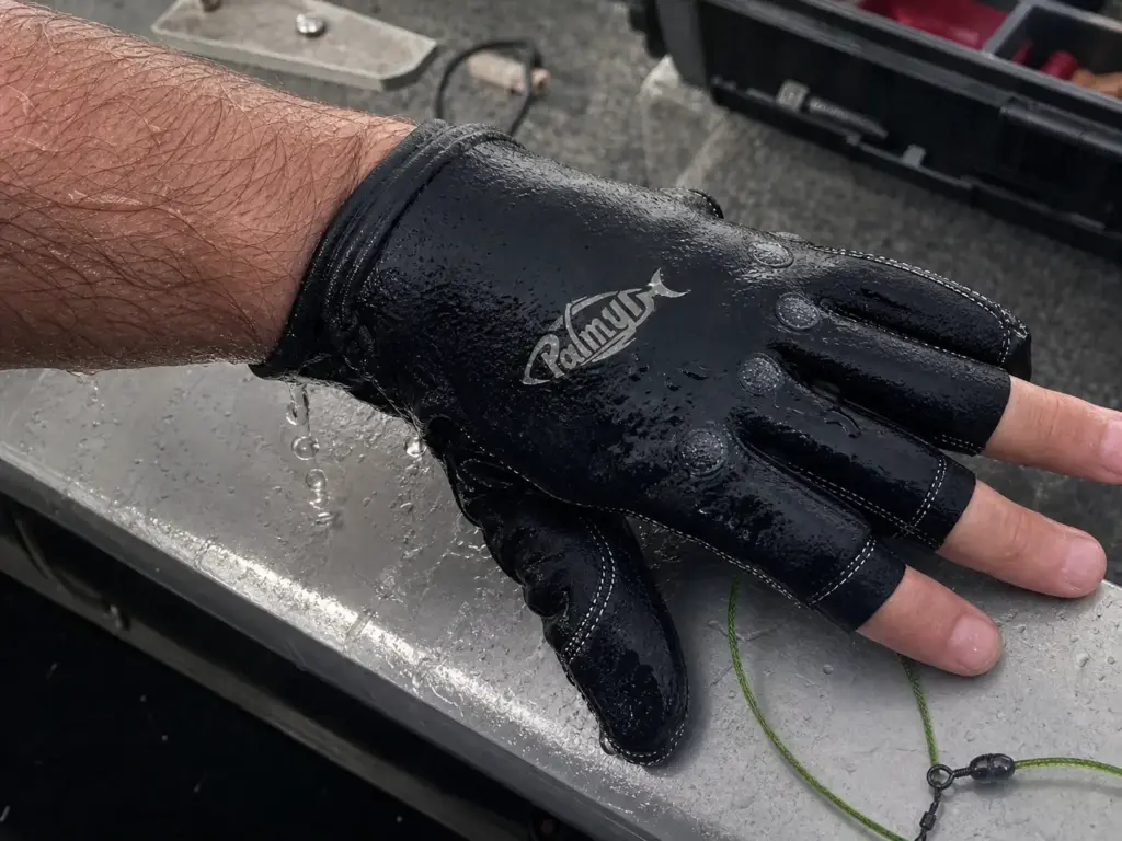 Soaked neoprene fishing glove dripping over the gunwale after a wet retrieve