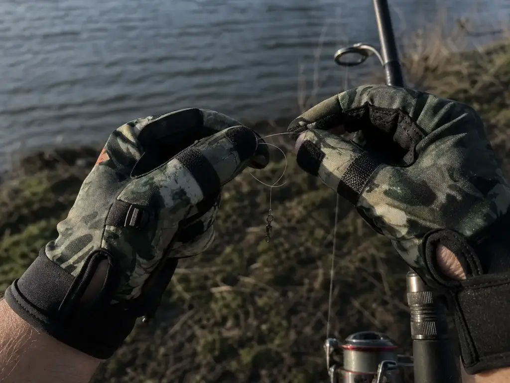Gloved fingers struggling to pinch fishing line with bunched fingertip material