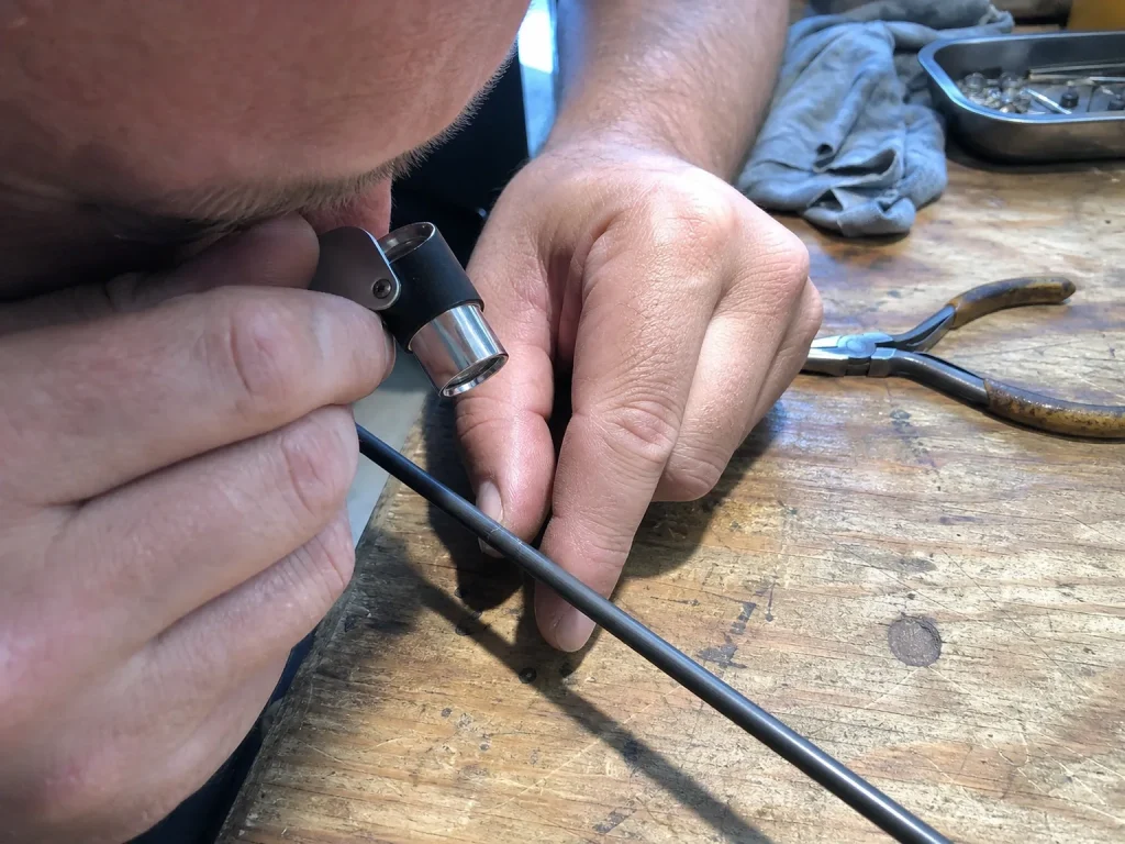 Inspecting a suspect spot on a rod blank with a 10x jeweler's loupe to confirm whitened fractured fiber